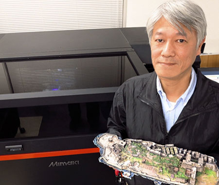 Susumu Fukunaga, Executive Director, standing in front of the